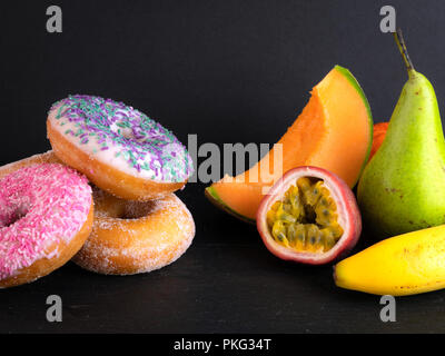 Donuts and fruit showing healthy and unhealthy foods Stock Photo
