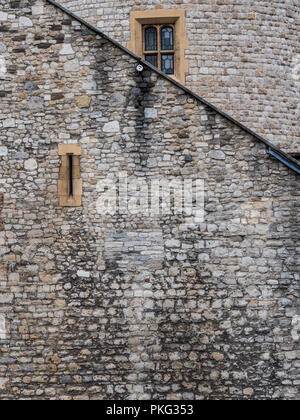A view of a very old stone wall with a narrow window and angled roof Stock Photo
