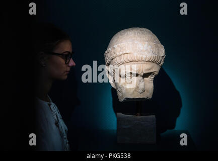13 September 2018, Rhineland-Palatinate, Speyer: A museum staff member looks at the original portrait head of a Roman emperor, presumably Valentinian I. in the exhibition. The head is on loan from the Ny Carlsberg Glyptotek Museum in Copenhagen. In an exhibition entitled 'Valentinian I and the Palatinate in Late Antiquity' (16 September 2018 to 11 August 2019), the Historical Museum of the Palatinate shows the work of the Roman Emperor Valentinian I during his period of office from 364 to 375 AD in the present Palatinate. Photo: Andreas Arnold/dpa