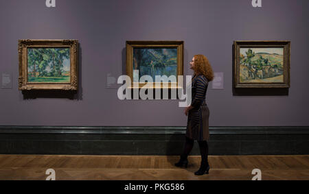 National Gallery, London, UK. 13 September, 2018. An exhibition bringing together the Impressionist and Post-Impressionist collections of the Courtauld Gallery and National Gallery with many iconic works of art on display, the exhibition runs from 17 September 2018 - 20 January 2019. Photo: Paul Cézanne, landscapes. Left: Tall Trees at the Jas de Bouffan, about 1883; Centre: Lac d’Annecy, 1896; Right: Farm in Normandy, Summer (Hattenville), about 1882. The Courtauld Gallery, London. Posed with gallery staff. Credit: Malcolm Park/Alamy Live News. Stock Photo