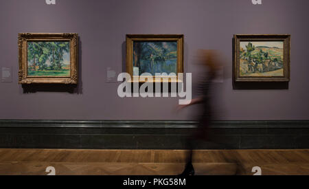 National Gallery, London, UK. 13 September, 2018. An exhibition bringing together the Impressionist and Post-Impressionist collections of the Courtauld Gallery and National Gallery with many iconic works of art on display, the exhibition runs from 17 September 2018 - 20 January 2019. Photo: Paul Cézanne, landscapes. Left: Tall Trees at the Jas de Bouffan, about 1883; Centre: Lac d’Annecy, 1896; Right: Farm in Normandy, Summer (Hattenville), about 1882. The Courtauld Gallery, London. Posed with gallery staff. Credit: Malcolm Park/Alamy Live News. Stock Photo