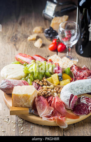 Mix of different snacks and appetizers. Spanish tapas or italian wine set on a wooden plate. Tapas bar. Nuts, olives, sausage, cheese, jamon, tomatoes Stock Photo