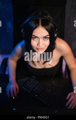 New level. Top view of confident strong female gamer sitting and looking at the camera while completing level and putting hands on keyboard and mouse Stock Photo