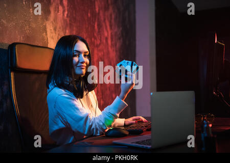 Smiling young rubber in sweatshirt with hood making purchases in internet and paying with stolen credit card Stock Photo