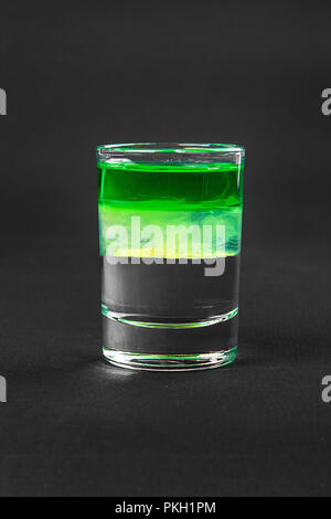 Multicolored layered cocktail, glass with transparent and colored drink with the taste of mint, banana, lemon, absinthe, alcoholic, side view isolated Stock Photo