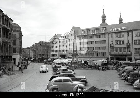 1950s, historical, post-war, City Centre, Koln, Germany, street-scene showing buildings and motorcars of the era in cobbled city square with outdoor market stalls. Old tram-lines seen in the picture. Stock Photo