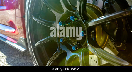 Shiny mag wheel of a red car with blue bolts Stock Photo