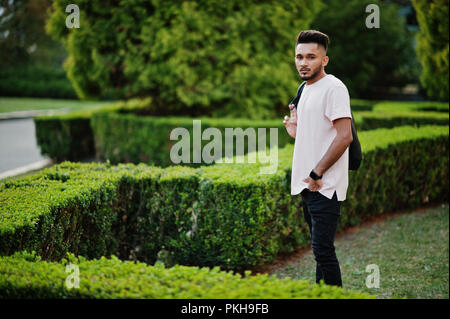 Young man with checked shirt posing in a garden, Pune, Maharashtra, India.  - SuperStock