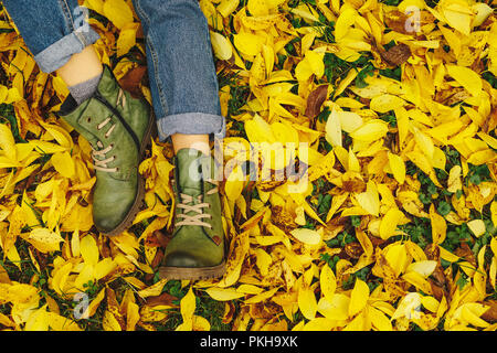 Conceptual image of legs in boots on the autumn leaves. Feet shoes resting in nature Stock Photo