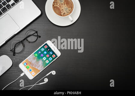 Kyiv, Ukraine - Fabruary 6, 2018: Apple iPhone 8 plus with social network apps on the screen with macbook, coffee and headphones on black desk, top vi