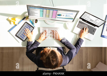 Overhead View Of A Businesswoman Doing Multitasking Work On Electronic Devices Stock Photo