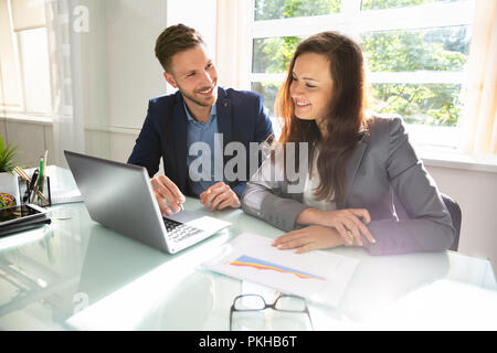 Two Happy Businesspeople Working On Laptop At Workplace Stock Photo