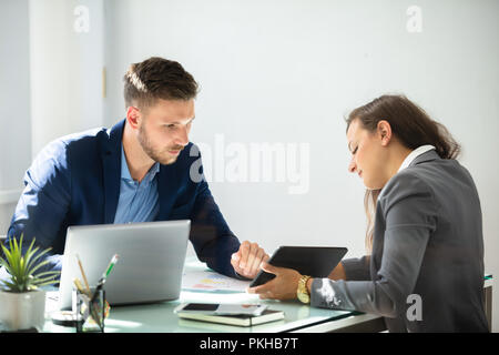 Two Young Businesspeople Using Digital Tablet At Workplace Stock Photo