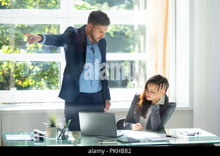 Angry Young Businessman Firing Upset Female Employee In Office Stock Photo