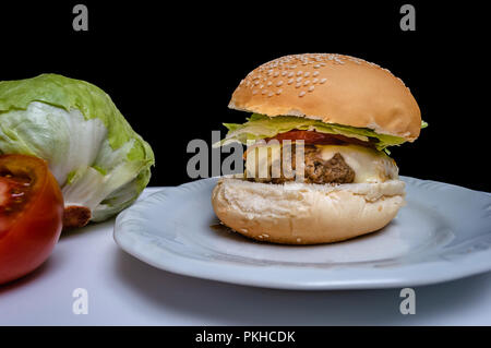 Cheeseburger with fresh tomato and lettuce isolated on black background Stock Photo
