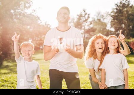 happy family with two kids playing with drone in park Stock Photo