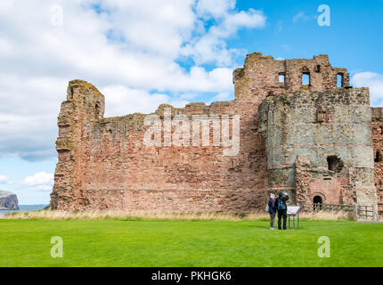 Couple reading information board at 14th century fortified Tantallon Castle, North Berwick, East Lothian, Scotland, UK Stock Photo