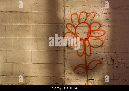 Sunflower painted on side of brick building in alley way. Stock Photo