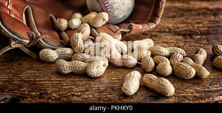 Baseball, glove and ball on rustic wood with scattered peanuts in the shell. Theme for America's favorite sport. Banner format. Nostalgia concept. Stock Photo