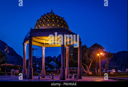 Gazebo dome bathed in yellow light. A romantic atmosphere during blue hour, from Muscat, Oman. Stock Photo