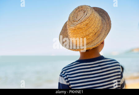 Boy with hat contemplating the landscape on a beach Stock Photo