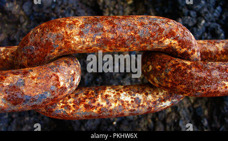 A large chain link in a long rusty chain holds a fishing boat to the harbour in Jersey, in the English Channel. Stock Photo