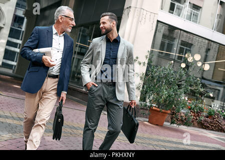 Two businessmen discussing about the new project while walking outdoors. Stock Photo