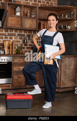 beautiful young repairwoman with tools and clipboard at kitchen Stock Photo