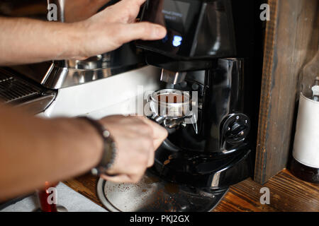 freshly ground coffee beans in a portafilter by the coffee grinder Stock Photo