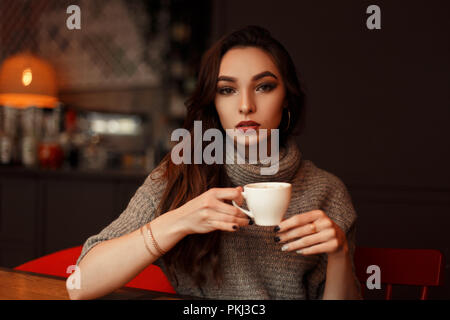 Beautiful woman with a cup of coffee drinks a delicious coffee in a cafe Stock Photo