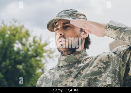 portrait of confident soldier in military uniform with cloudy sky on background Stock Photo
