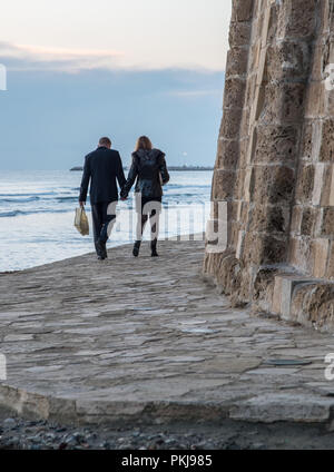 Larnaca, Cyprus - January 01 2018: Young unrecognized couple holding hands walking at near the castle at Larnaca city in Cyprus Stock Photo