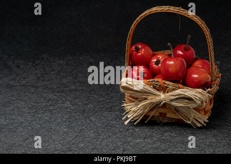 Apples in a straw basket over a black background. Fall and autumn concept Stock Photo