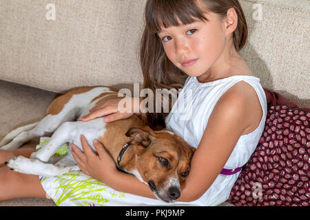 A six year old girl holding her female pet on a sofa Stock Photo