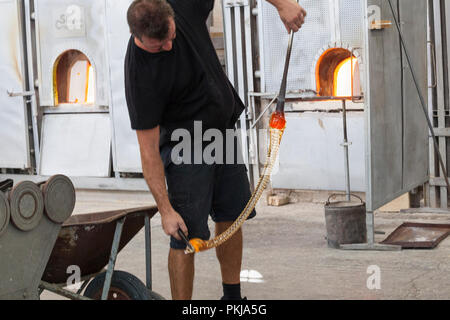 Glassblower producing a chandelier in Simone Cenedese Fornace, Murano, Venice,  Venice, Italy during Glass Week. Rapidly twisting the molten glass for Stock Photo