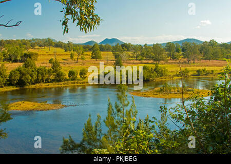 Australian landscape with blue waters of Bellinger River slicing through valley cloaked in golden grasses and trees under blue sky near Dorrigo NSW Stock Photo