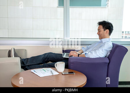 Adult Asian man working on his laptop Stock Photo