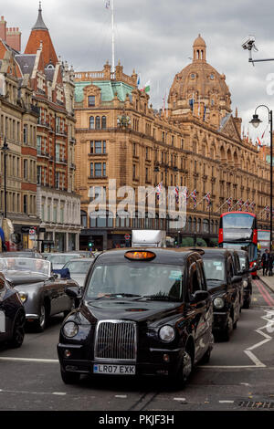 Black taxi cabs on Brompton Road in Knightsbridge with Harrods in the background, London England United Kingdom UK Stock Photo