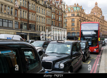 Black taxi cabs on Brompton Road in Knightsbridge with Harrods in the background, London England United Kingdom UK Stock Photo