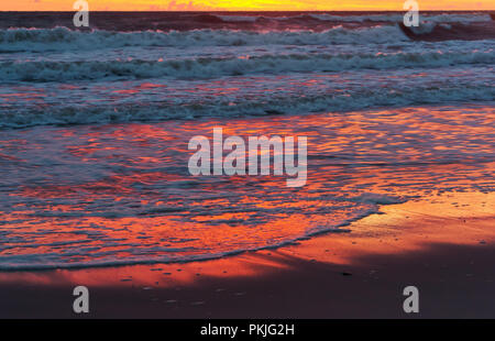 Sunset over the sea. Reflection of sunlight in the sea waves. Red sky in the rays of the sunset. Stock Photo