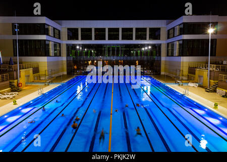 The outdoor swimming pool of the city of Khabarovsk, located on the embankment of the Amur river. In the evening by the light of lanterns. Bright blue Stock Photo