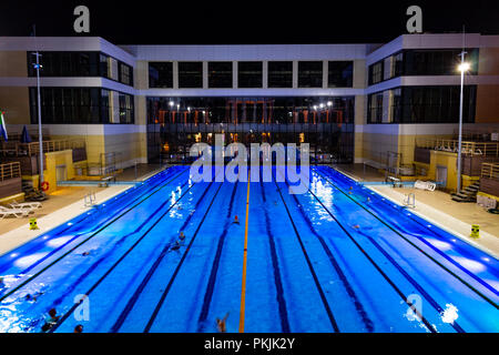 The outdoor swimming pool of the city of Khabarovsk, located on the embankment of the Amur river. In the evening by the light of lanterns. Bright blue Stock Photo