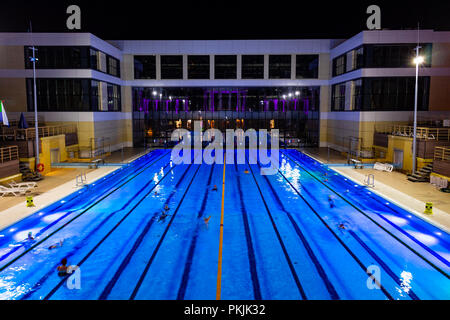 The outdoor swimming pool of the city of Khabarovsk, located on the embankment of the Amur river. In the evening by the light of lanterns. Bright blue Stock Photo