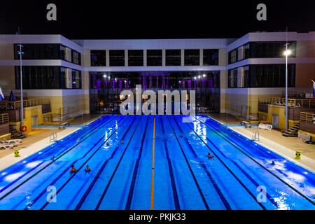 The outdoor swimming pool of the city of Khabarovsk, located on the embankment of the Amur river. In the evening by the light of lanterns. Bright blue Stock Photo