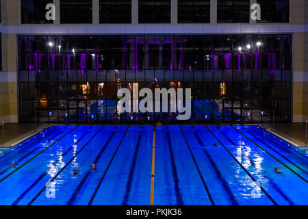 The outdoor swimming pool of the city of Khabarovsk, located on the embankment of the Amur river. In the evening by the light of lanterns. Bright blue Stock Photo