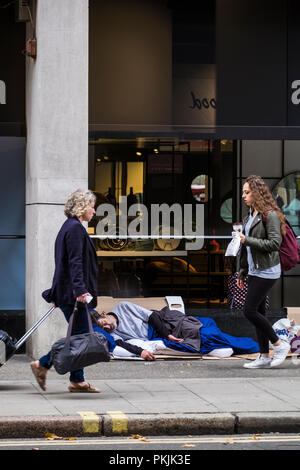 People walking past rough sleeper on the street in the Borough of Camden, London, England, U.K. Stock Photo