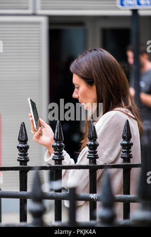 People using mobile devices out on the street, City of Westminster, London, England, U.K. Stock Photo
