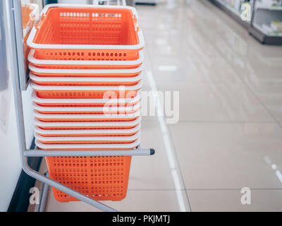Row of orange shopping basket in storage shelf on the clean floor with copy space. Shopping basket service for customer using in mini mart. Stock Photo