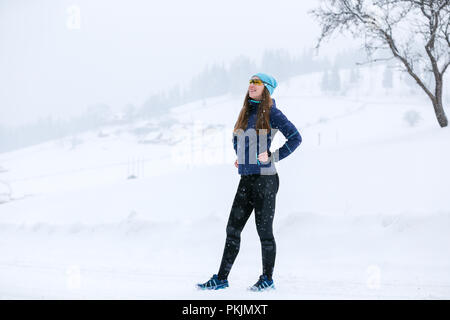 Young runner woman standing at the road in winter Stock Photo