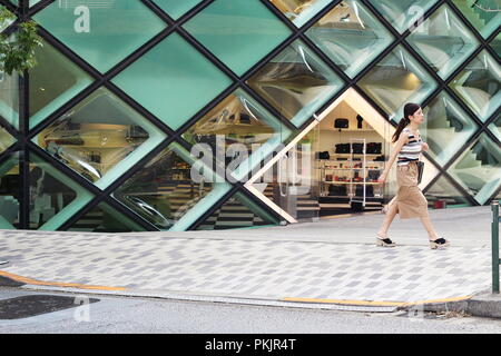 A pedestrian walks past the distinctive Herzog and de Meuron-designed Prada store in Aoyama. Stock Photo